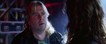 Movie still from “Rock Star” (2001), directed by Stephen Herek – A man with long blonde hair is looking at a woman in a leather jacket; Close Up shot, Over the shoulder angle