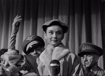 Movie still from “Roman Holiday” (1953), directed by William Wyler – An old photo of a woman and two men; Medium shot, Low angle