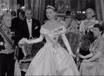 Movie still from “Roman Holiday” (1953), directed by William Wyler – An old photo of a woman in a ball gown; Medium shot, Low angle