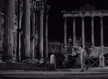Movie still from “Roman Holiday” (1953), directed by William Wyler – A black and white photo of a man walking in front of an old building; Wide shot, Low angle