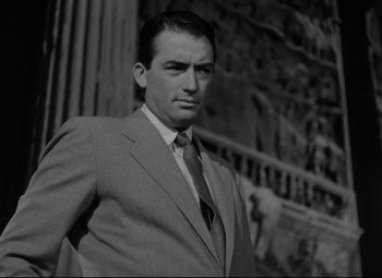 Movie still from “Roman Holiday” (1953), directed by William Wyler – Black and white photograph of a man wearing a suit and tie; Medium shot, Low angle