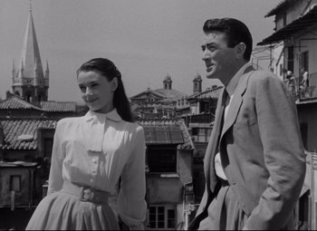 Movie still from “Roman Holiday” (1953), directed by William Wyler – A man and a woman standing next to each other; Medium shot, Low angle