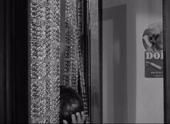 A black and white photo of a person looking out a window