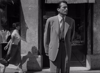 Movie still from “Roman Holiday” (1953), directed by William Wyler – A black and white photo of a man in a suit; Medium shot, Low angle