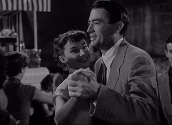 Movie still from “Roman Holiday” (1953), directed by William Wyler – A man and a woman are dancing together; Medium shot, Low angle