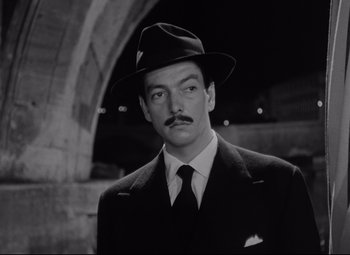 Movie still from “Roman Holiday” (1953), directed by William Wyler – A black and white photo of a man in a suit and hat; Close Up shot, Low angle