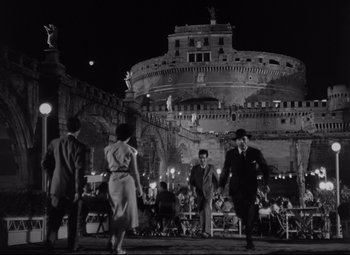 Movie still from “Roman Holiday” (1953), directed by William Wyler – A black and white photo of people dancing in front of a castle; Extreme Wide shot, Low angle