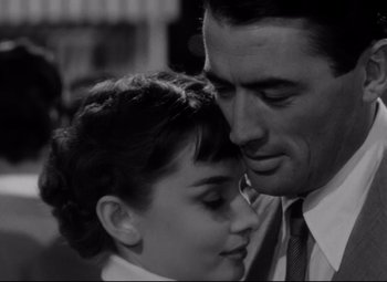 Movie still from “Roman Holiday” (1953), directed by William Wyler – A man and a woman embracing each other in a black and white photo; Close Up shot, Low angle