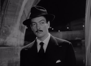 Movie still from “Roman Holiday” (1953), directed by William Wyler – A black and white photo of a man in a suit and hat; Close Up shot, Low angle