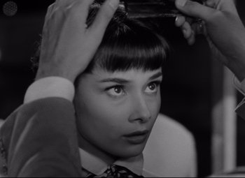 Movie still from “Roman Holiday” (1953), directed by William Wyler – A black - and - white photo of a woman getting her hair cut; Close Up shot, Over the shoulder angle