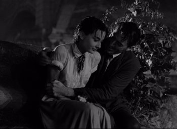 Movie still from “Roman Holiday” (1953), directed by William Wyler – A man and a woman sitting next to each other on top of a bench; Medium shot, Low angle