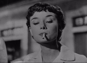 Movie still from “Roman Holiday” (1953), directed by William Wyler – A black - and - white photo of a woman smoking a cigarette; Close Up shot, Low angle