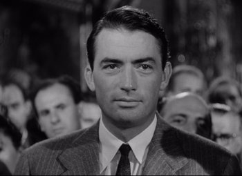 Movie still from “Roman Holiday” (1953), directed by William Wyler – A black and white photo of a man in a suit and tie; Close Up shot, Low angle