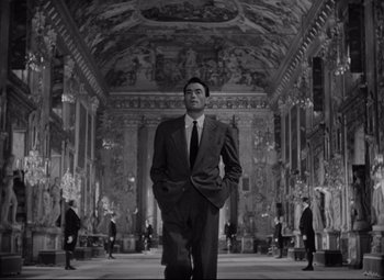 Movie still from “Roman Holiday” (1953), directed by William Wyler – A black and white photo of a man in a suit and tie; Wide shot, Low angle