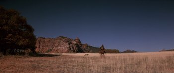 Movie still from “Romancing the Stone” (1984), directed by Robert Zemeckis – A man riding a horse through a field with mountains in the background; Extreme Wide shot, Low angle