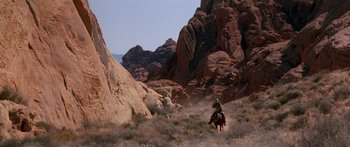 Movie still from “Romancing the Stone” (1984), directed by Robert Zemeckis – A man riding a horse through the desert; Extreme Wide shot, High angle