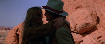 Movie still from “Romancing the Stone” (1984), directed by Robert Zemeckis – A man and a woman embracing in front of a rock wall; Close Up shot, Low angle