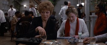 Movie still from “Romancing the Stone” (1984), directed by Robert Zemeckis – Two women sitting at a table in a restaurant; Medium shot, Over the shoulder angle