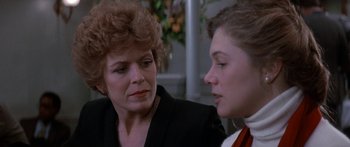 Movie still from “Romancing the Stone” (1984), directed by Robert Zemeckis – A woman sitting next to another woman in front of a window; Close Up shot, Over the shoulder angle