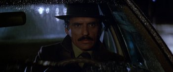 Movie still from “Romancing the Stone” (1984), directed by Robert Zemeckis – A man with a mustache and a hat in a car; Close Up shot, Low angle