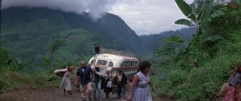 Movie still from “Romancing the Stone” (1984), directed by Robert Zemeckis – A group of people walking down a dirt road near a bus; Wide shot, High angle