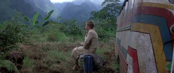 Movie still from “Romancing the Stone” (1984), directed by Robert Zemeckis – A woman sitting on top of a suitcase in a field; Wide shot, High angle