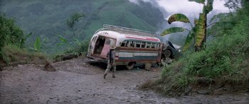 Movie still from “Romancing the Stone” (1984), directed by Robert Zemeckis – A man walking near an abandoned bus on a dirt road; Wide shot, High angle
