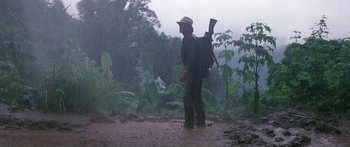 Movie still from “Romancing the Stone” (1984), directed by Robert Zemeckis – A man with a backpack standing in the rain; Wide shot, Low angle