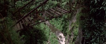 Movie still from “Romancing the Stone” (1984), directed by Robert Zemeckis – An old wooden bridge over a river in the woods; Extreme Wide shot, Overhead angle