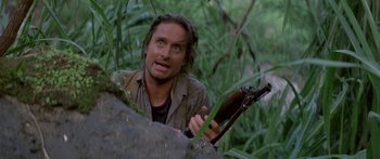 Movie still from “Romancing the Stone” (1984), directed by Robert Zemeckis – A man holding a rifle in the woods; Close Up shot, Low angle