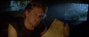 Movie still from “Romancing the Stone” (1984), directed by Robert Zemeckis – A man looking at a piece of paper in a dark room; Close Up shot, Over the shoulder angle