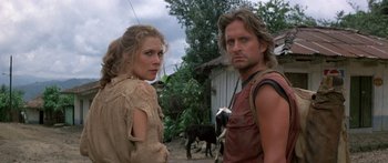 Movie still from “Romancing the Stone” (1984), directed by Robert Zemeckis – A man and a woman standing next to each other in front of a cow; Close Up shot, Low angle