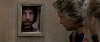 Movie still from “Romancing the Stone” (1984), directed by Robert Zemeckis – A man looking into a mirror while another man looks on; Close Up shot, Over the shoulder angle