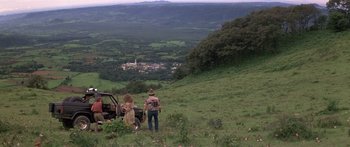 Movie still from “Romancing the Stone” (1984), directed by Robert Zemeckis – Two people standing on a hill looking out at a town; Extreme Wide shot, High angle
