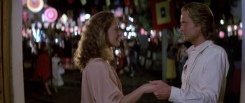 Movie still from “Romancing the Stone” (1984), directed by Robert Zemeckis – A woman is holding a man's hand outside; Medium shot, Over the shoulder angle