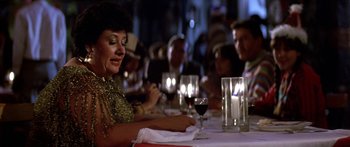 Movie still from “Romancing the Stone” (1984), directed by Robert Zemeckis – A group of people sitting at a table with candles; Close Up shot, Over the shoulder angle