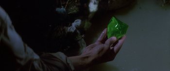 Movie still from “Romancing the Stone” (1984), directed by Robert Zemeckis – A person holding a green object in their hand; Close Up shot, High angle