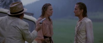 Movie still from “Romancing the Stone” (1984), directed by Robert Zemeckis – A woman holding a gun while standing next to a car; Medium shot, Over the shoulder angle