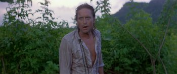 Movie still from “Romancing the Stone” (1984), directed by Robert Zemeckis – A man with wet hair standing in a field; Close Up shot, Over the shoulder angle