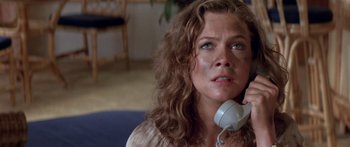 Movie still from “Romancing the Stone” (1984), directed by Robert Zemeckis – A person talking on a phone; Close Up shot, High angle