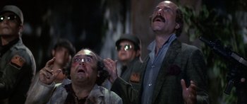 Movie still from “Romancing the Stone” (1984), directed by Robert Zemeckis – A group of men standing next to each other in a room; Medium shot, Low angle