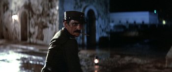 Movie still from “Romancing the Stone” (1984), directed by Robert Zemeckis – A man with a pipe in his mouth and wearing a military uniform; Close Up shot, Low angle