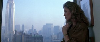 Movie still from “Romancing the Stone” (1984), directed by Robert Zemeckis – A woman standing in front of a city skyline; Close Up shot, Over the shoulder angle