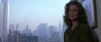 Movie still from “Romancing the Stone” (1984), directed by Robert Zemeckis – A woman standing in front of a city skyline; Close Up shot, Low angle