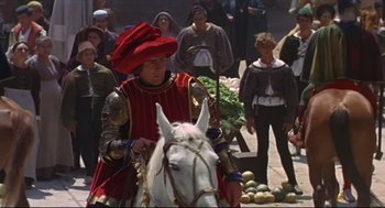 Movie still from “Romeo and Juliet” (1968), directed by Franco Zeffirelli – A man riding on the back of a white horse down a street; Medium shot, High angle
