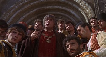 Movie still from “Romeo and Juliet” (1968), directed by Franco Zeffirelli – A group of men standing in a tunnel with one man wearing a crown; Medium shot, Low angle