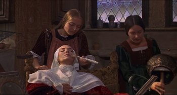Movie still from “Romeo and Juliet” (1968), directed by Franco Zeffirelli – A woman is getting her face waxed by two other women; Medium shot, High angle