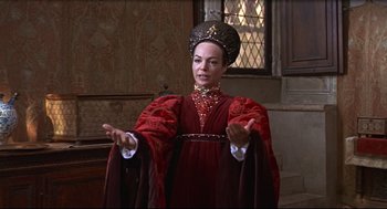 Movie still from “Romeo and Juliet” (1968), directed by Franco Zeffirelli – A woman dressed in a red dress and a black hat; Medium shot, Over the shoulder angle