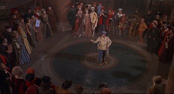 Movie still from “Romeo and Juliet” (1968), directed by Franco Zeffirelli – A group of people standing in a circle with a man in the middle of the circle; Wide shot, High angle