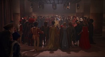 Movie still from “Romeo and Juliet” (1968), directed by Franco Zeffirelli – A group of people standing around a room; Wide shot, High angle